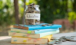 Jar with coins labeled "education" sitting on top of a stack of books