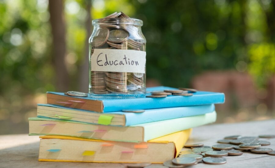Jar with coins labeled "education" sitting on top of a stack of books