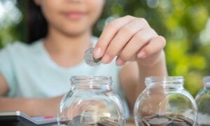 Young girl putting coins into a piggy bank