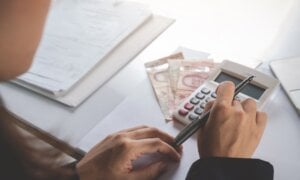 Person working at a desk with money and a calculator