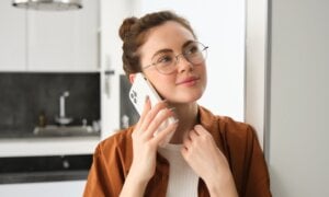 Portrait of happy woman at home, answers phone call, talking on mobile, holding smartphone and smiling.