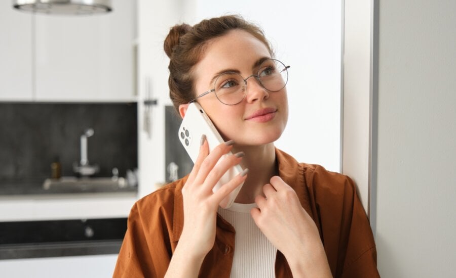 Portrait of happy woman at home, answers phone call, talking on mobile, holding smartphone and smiling.