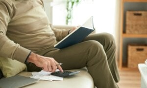 Man sitting on couch with calculator and notebook