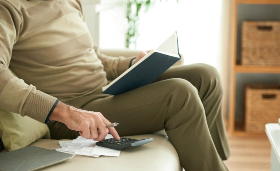 Man sitting on couch with calculator and notebook