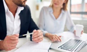 Man and woman sitting at a desk with a laptop