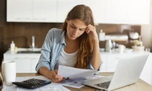 Woman sitting at table working with laptop and papers