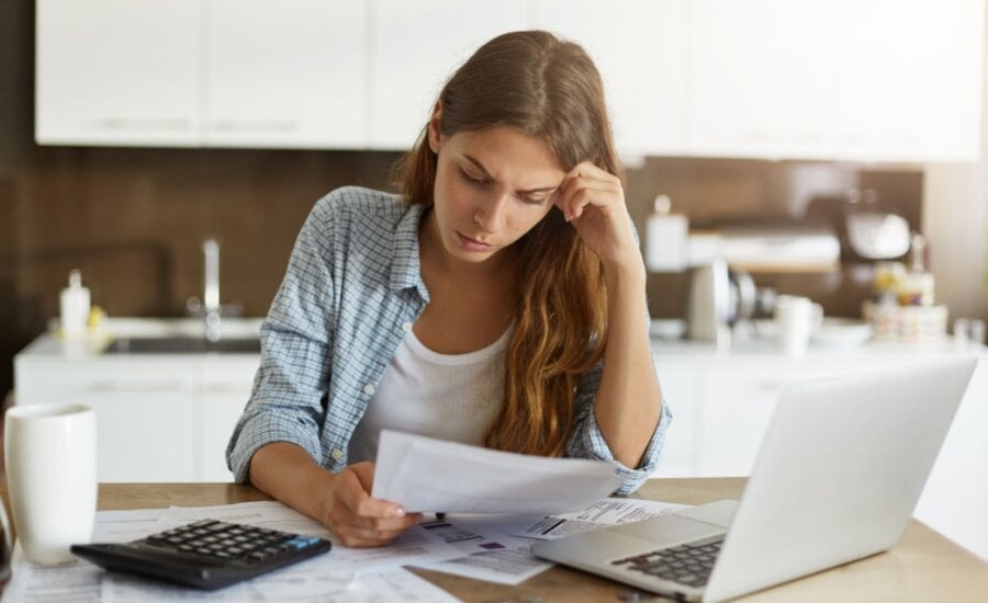 Woman sitting at table working with laptop and papers
