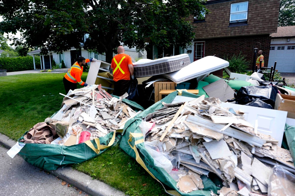Municipal garbage contractors remove garbage from homes that flooded during the storm on Canada Day, in the Qualicum – Graham Park neighbourhood of Ottawa, on Tuesday, July 7, 2026.