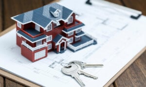 Villa house model, key and drawing on retro desktop (real estate sale concept)
