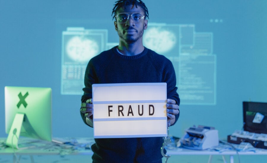 Man is seen holding a sign that reads fraud.
