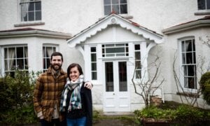 Portrait of couple standing near a new house with arms around