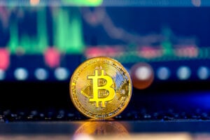 Golden Bitcoin coin on keyboard with beautiful background. Stock market trading chart background online candlestick on cryptocurrency platform. Cryptocurrency money concept.