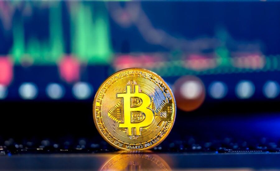 Golden Bitcoin coin on keyboard with beautiful background. Stock market trading chart background online candlestick on cryptocurrency platform. Cryptocurrency money concept.