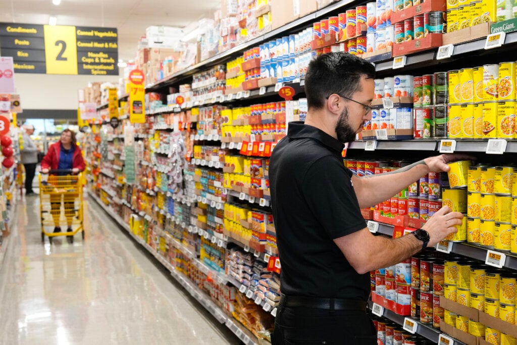 An employee stocks shelves while customers shop at a No Frills store in Toronto, on Friday, Oct. 9, 2026.